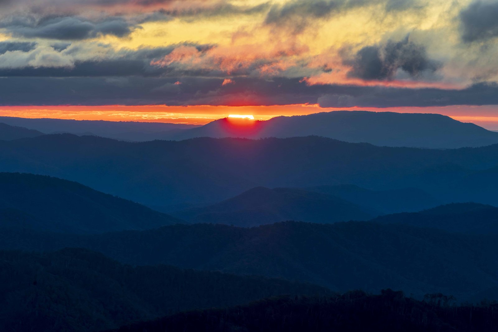 Sunrise over mountain ranges with dramatic cloud layers