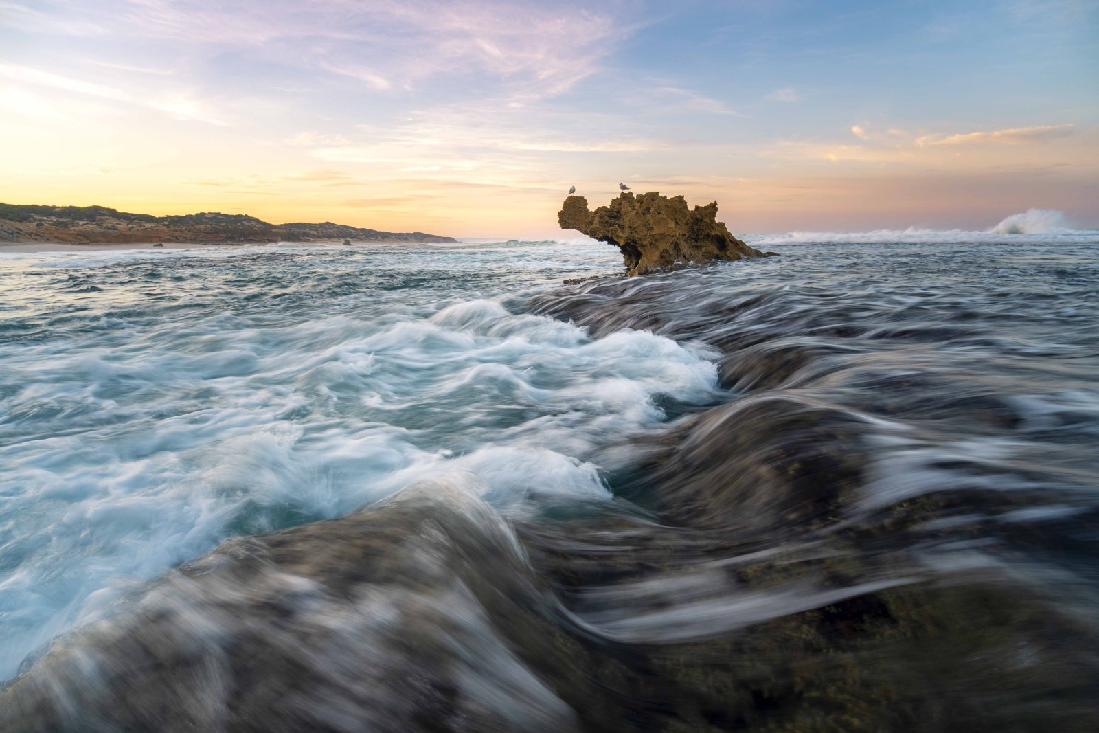Long exposure seascape at sunset with waves flowing over rocks